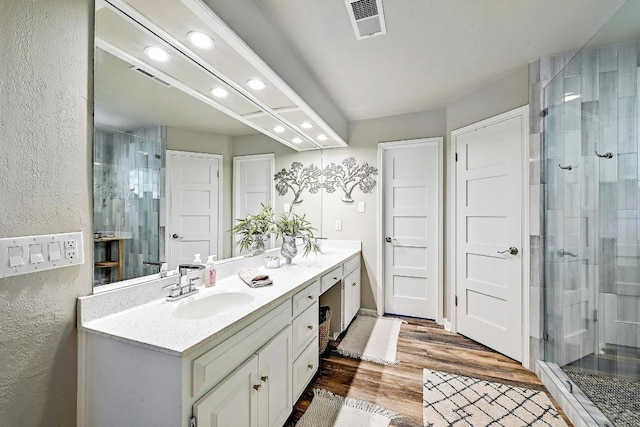 409 Hurst Creek Rd, Lakeway, TX 78734 - bathroom with double vanity, recessed lighting, wood finished floors, a stall shower, and a textured wall