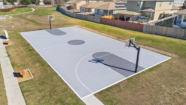 view of basketball court featuring fence, a lawn, community basketball court, and a residential view