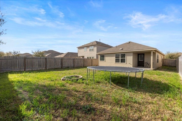 back of property with a trampoline, a lawn, and a fenced backyard