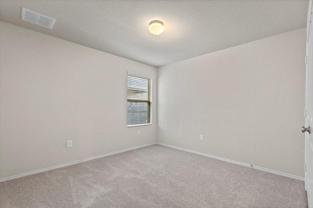 carpeted spare room featuring a textured ceiling, visible vents, and baseboards