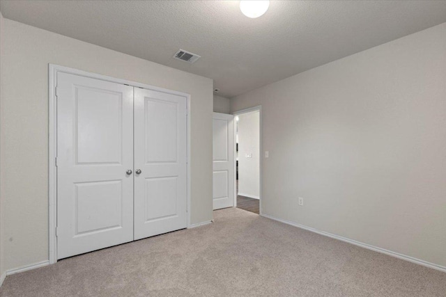 unfurnished bedroom featuring baseboards, visible vents, carpet, and a closet