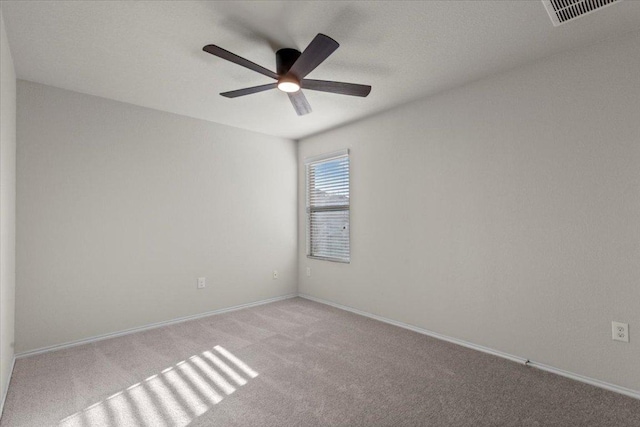 spare room featuring carpet floors, a ceiling fan, visible vents, and baseboards