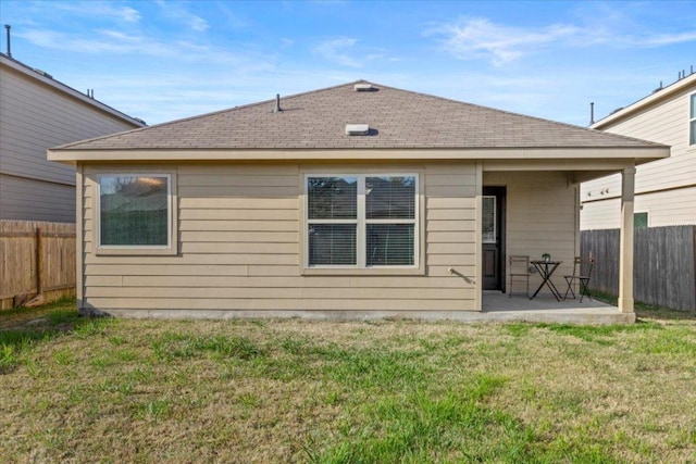 rear view of house featuring a fenced backyard, roof with shingles, a yard, and a patio