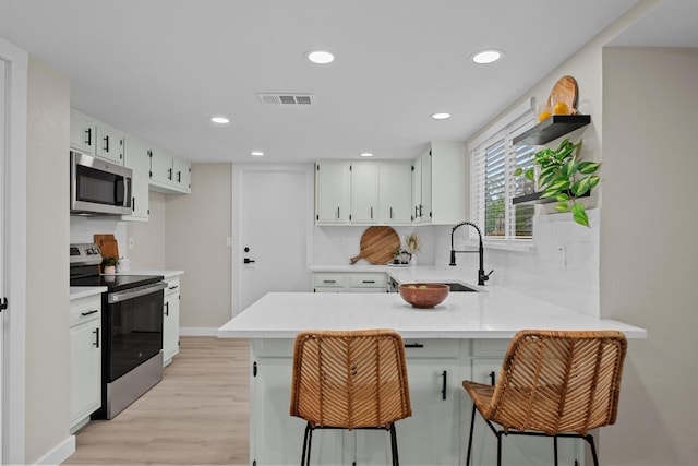 3005 Canter Ln, Austin, TX 78759 - kitchen with appliances with stainless steel finishes, a peninsula, light wood-style flooring, a sink, and light countertops