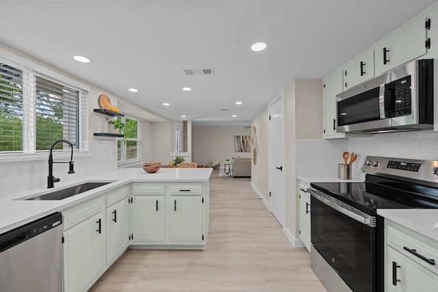 3005 Canter Ln, Austin, TX 78759 - kitchen featuring stainless steel appliances, a sink, light wood-type flooring, a peninsula, and decorative backsplash