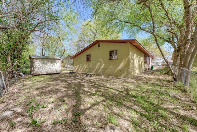 back of house featuring an outdoor structure, fence, and a storage unit