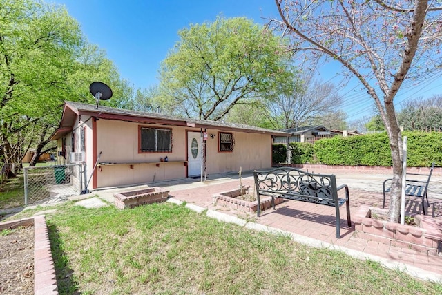 view of front of house featuring a vegetable garden, cooling unit, a patio area, fence, and a front lawn