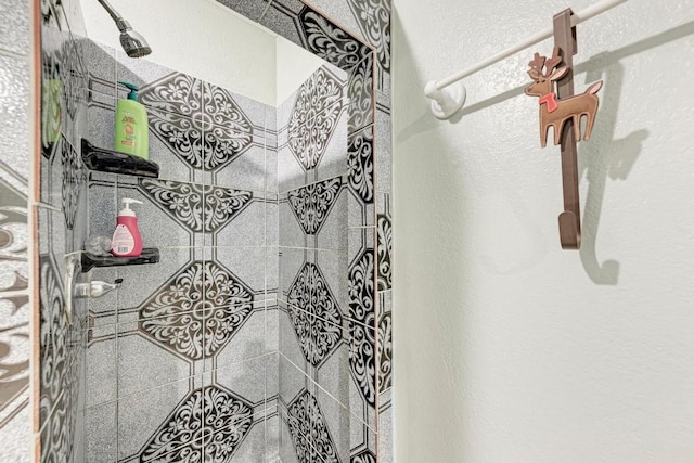bathroom featuring a textured wall and a tile shower