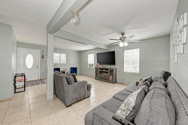 living area with light tile patterned flooring, ceiling fan, and beam ceiling