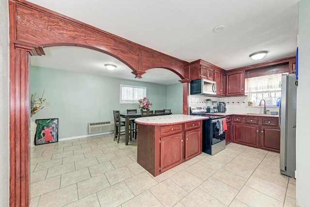 kitchen featuring plenty of natural light, light tile patterned floors, a peninsula, light countertops, and stainless steel appliances