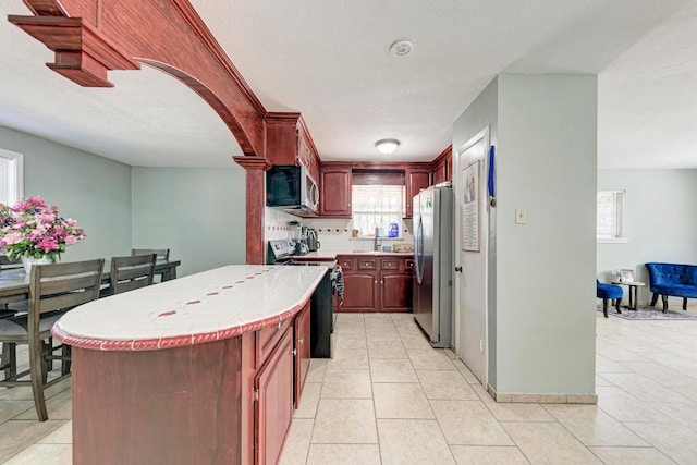 kitchen with stainless steel appliances, tile countertops, a sink, and dark brown cabinets