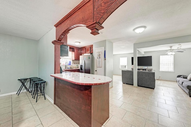 kitchen with a peninsula, a sink, a wealth of natural light, and stainless steel refrigerator with ice dispenser