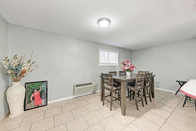 dining space with baseboards, a textured ceiling, tile patterned flooring, and a wall unit AC