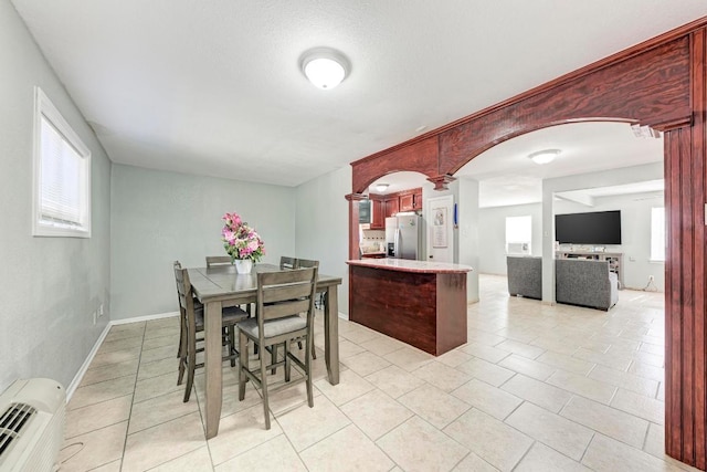dining space featuring light tile patterned floors, ornate columns, arched walkways, and a wall mounted air conditioner