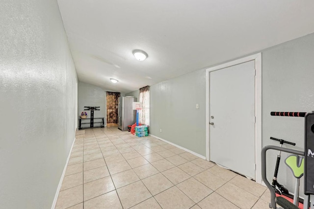 interior space with light tile patterned flooring, baseboards, and vaulted ceiling