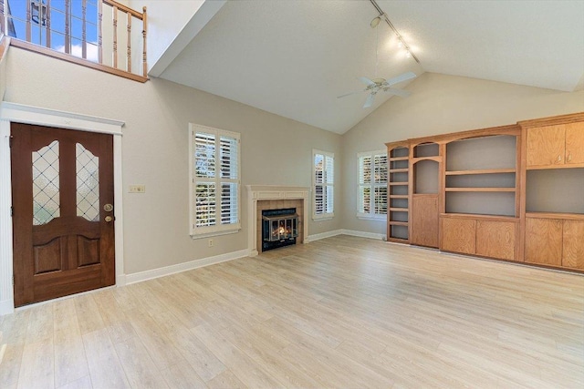 7304 Halbert Dr, Austin, TX 78750 - unfurnished living room with rail lighting, a ceiling fan, light wood finished floors, high vaulted ceiling, and a tiled fireplace