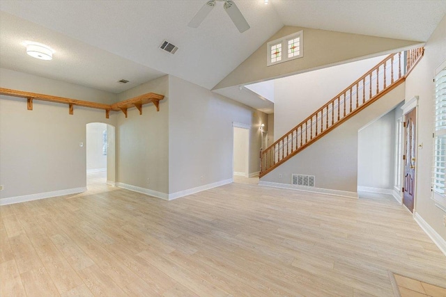 7304 Halbert Dr, Austin, TX 78750 - unfurnished living room featuring ceiling fan, arched walkways, high vaulted ceiling, wood finished floors, and stairs