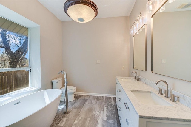 7304 Halbert Dr, Austin, TX 78750 - bathroom with a freestanding bath, double vanity, toilet, and baseboards