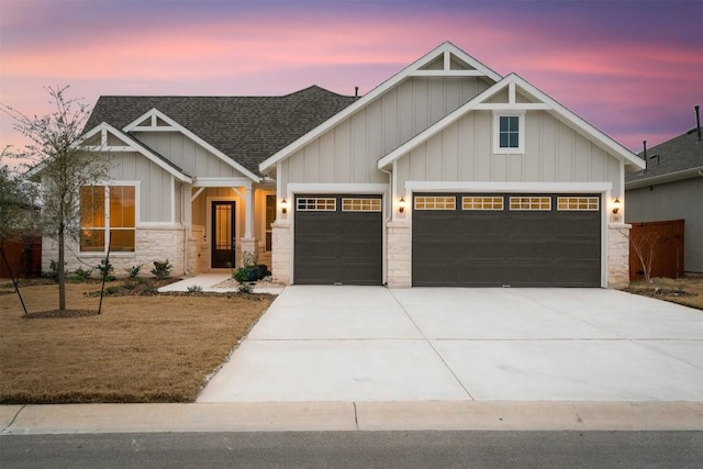 195 Barn Hill Loop, Dripping Springs, TX 78620 - view of front facade with board and batten siding, roof with shingles, a garage, driveway, and stone siding