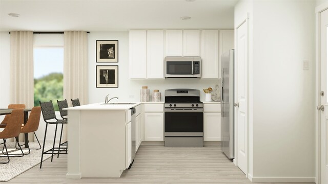 kitchen with a sink, appliances with stainless steel finishes, a peninsula, light wood-style flooring, and white cabinets