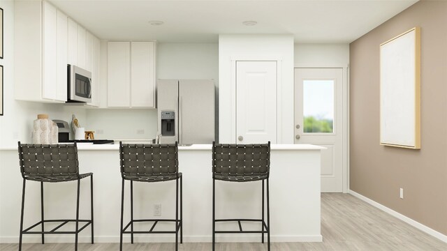 kitchen featuring light countertops, stainless steel microwave, a breakfast bar, a peninsula, and white fridge with ice dispenser