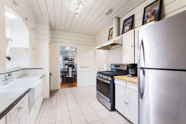 2310 Euclid Ave, Austin, TX 78704 - kitchen with stainless steel appliances, light tile patterned flooring, white cabinetry, under cabinet range hood, and wooden ceiling
