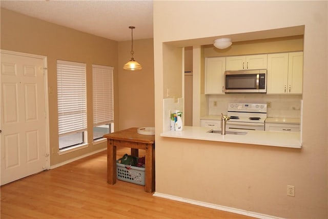 2706 Salado St Unit 210, Austin, TX 78705 - kitchen with stainless steel microwave, white electric stove, light wood-style floors, hanging light fixtures, and a peninsula