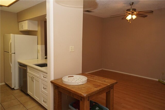 2706 Salado St Unit 210, Austin, TX 78705 - kitchen with dishwasher, white cabinets, a ceiling fan, light countertops, and freestanding refrigerator