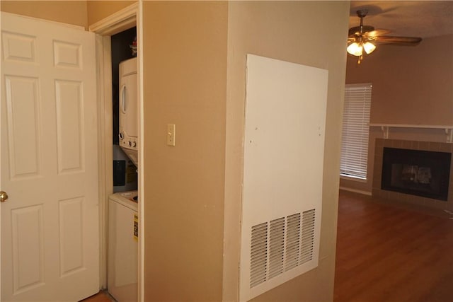 2706 Salado St Unit 210, Austin, TX 78705 - washroom featuring stacked washing machine and dryer, a ceiling fan, a tile fireplace, and wood finished floors