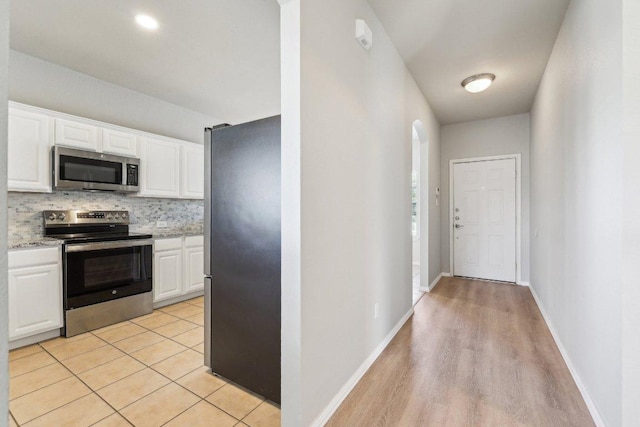211 Almquist St, Hutto, TX 78634 - kitchen featuring stainless steel appliances, white cabinets, backsplash, and light wood-style floors