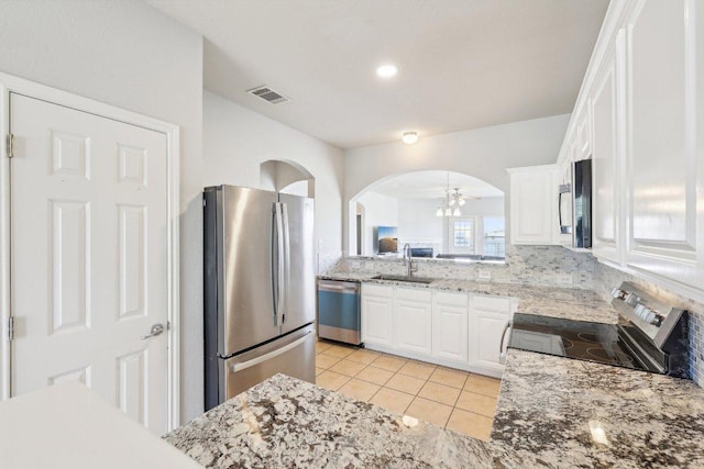 211 Almquist St, Hutto, TX 78634 - kitchen featuring stainless steel appliances, light tile patterned floors, white cabinets, ceiling fan, and arched walkways