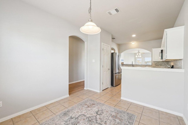 211 Almquist St, Hutto, TX 78634 - kitchen with arched walkways, stainless steel appliances, light tile patterned floors, and white cabinetry