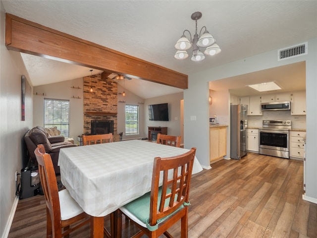 100 Stubblefield Dr, Elgin, TX 78621 - dining space with a fireplace, light wood-type flooring, a chandelier, and ceiling fan