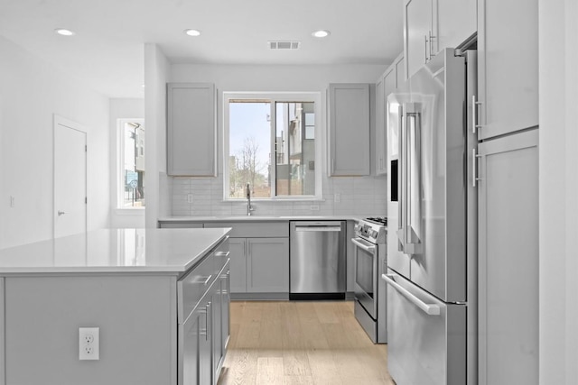 2209 Mcfly Pl, Austin, TX 78723 - kitchen with appliances with stainless steel finishes, gray cabinetry, light countertops, light wood finished floors, and recessed lighting