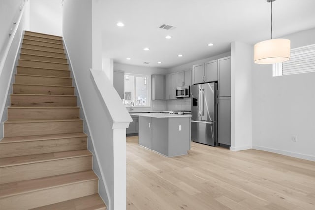 2209 Mcfly Pl, Austin, TX 78723 - kitchen with stainless steel appliances, a kitchen island, gray cabinetry, tasteful backsplash, and light countertops