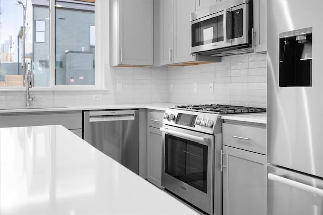 2209 Mcfly Pl, Austin, TX 78723 - kitchen featuring appliances with stainless steel finishes, gray cabinets, backsplash, light countertops, and a sink