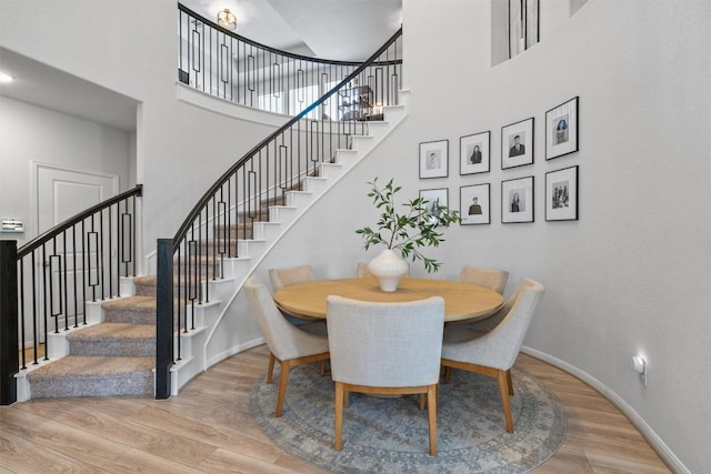 dining area with baseboards, a high ceiling, wood finished floors, and stairway