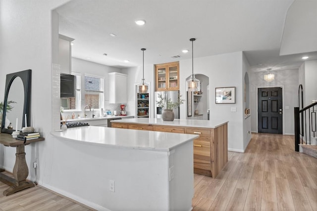 kitchen with light wood-style floors, light countertops, arched walkways, recessed lighting, and a kitchen island