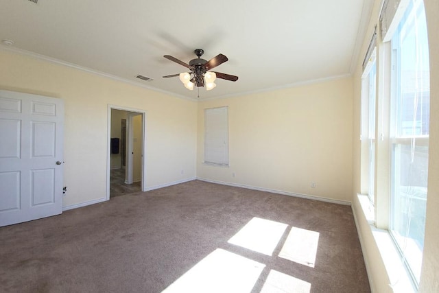 empty room with visible vents, crown molding, carpet, and a ceiling fan