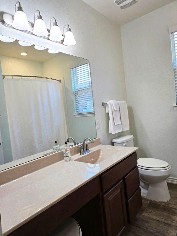 bathroom featuring visible vents, wood finished floors, toilet, and vanity