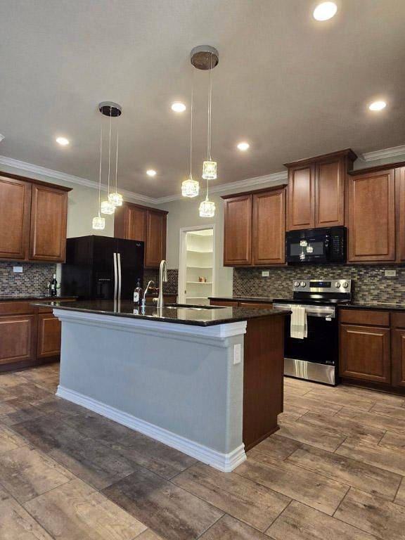 kitchen with a center island with sink, dark countertops, decorative light fixtures, and black appliances