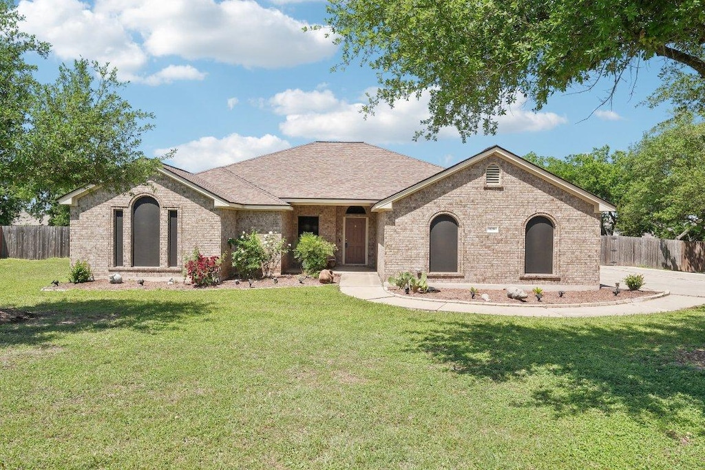 ranch-style house with a front yard, fence, and brick siding