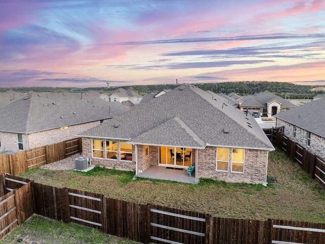 2233 Bravo Pass, Leander, TX 78641 - back of house at dusk featuring roof with shingles, central AC unit, a patio area, a fenced backyard, and brick siding