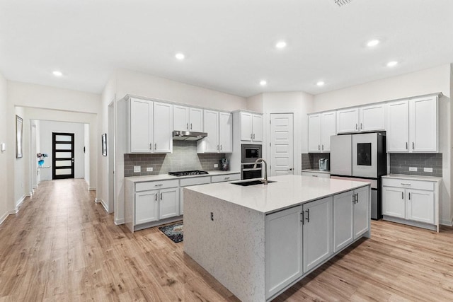 2233 Bravo Pass, Leander, TX 78641 - kitchen with a sink, appliances with stainless steel finishes, tasteful backsplash, light wood finished floors, and recessed lighting
