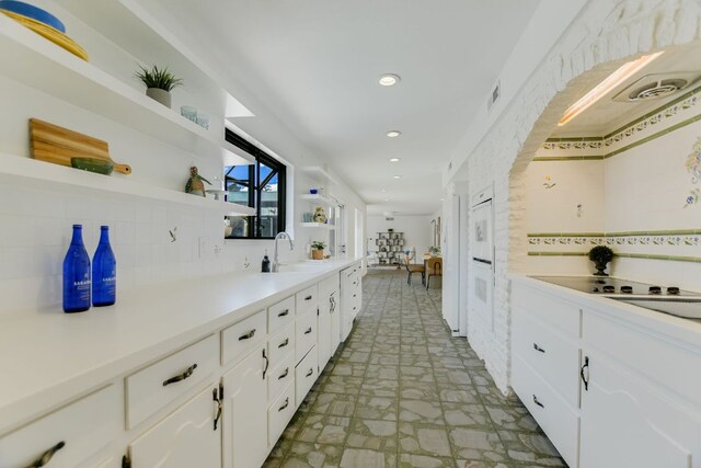 910 Old Stonehedge St, Austin, TX 78746 - kitchen with open shelves, backsplash, stone finish flooring, white cabinetry, and recessed lighting