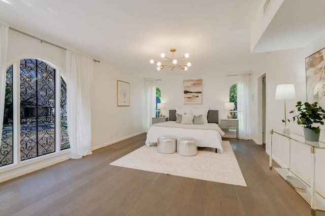 910 Old Stonehedge St, Austin, TX 78746 - bedroom featuring multiple windows, wood finished floors, and a chandelier