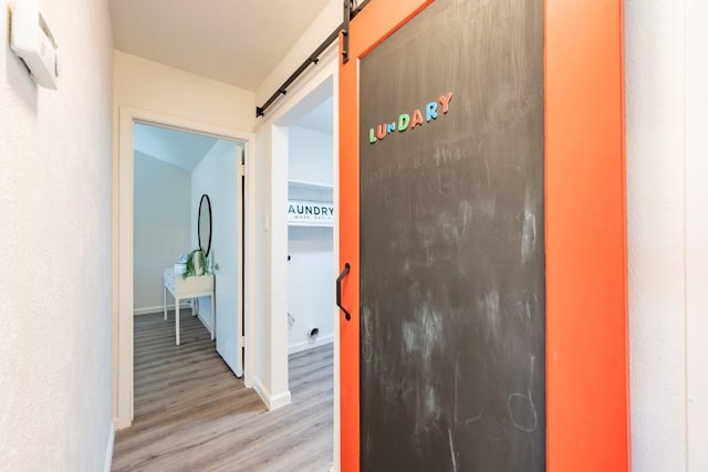 12303 Bainbridge Ln, Austin, TX 78750 - corridor featuring a barn door, light wood-style flooring, and baseboards
