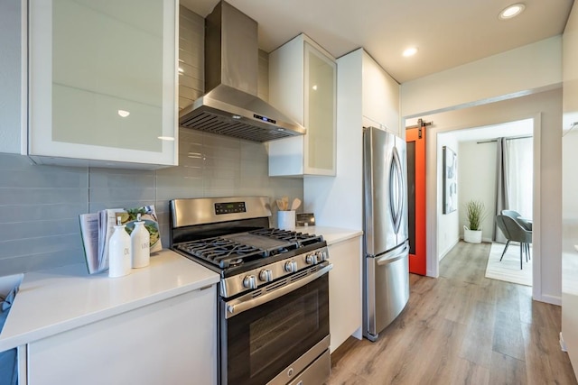 12303 Bainbridge Ln, Austin, TX 78750 - kitchen featuring appliances with stainless steel finishes, wall chimney exhaust hood, white cabinetry, light wood-style floors, and light countertops