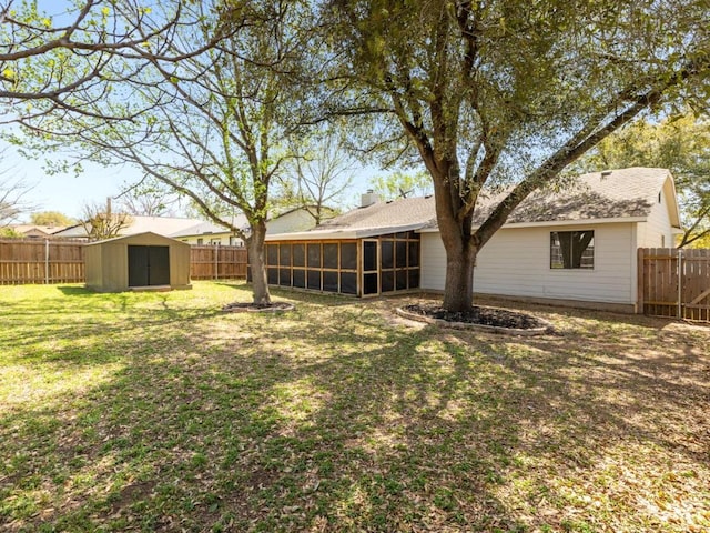 view of yard featuring a sunroom, a storage unit, a fenced backyard, and an outbuilding