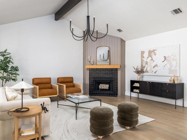 living room with beamed ceiling, visible vents, wood finished floors, and a tile fireplace